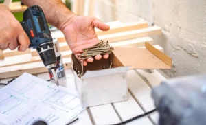 Close-up of a contractor using a cordless drill and construction screws during a residential carpentry and home improvement project.