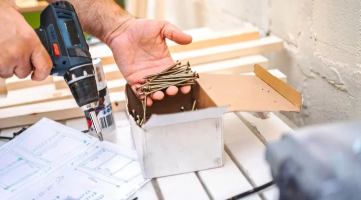 Close-up of a contractor using a cordless drill and construction screws during a residential carpentry and home improvement project.