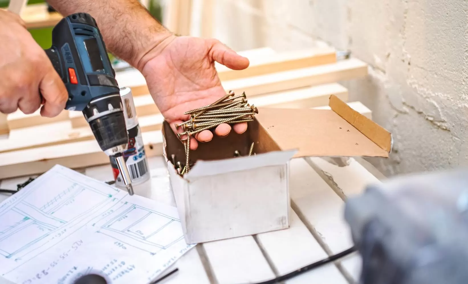 handyman-carpentry-and-fastener-installation Close-up of a contractor using a cordless drill and construction screws during a residential carpentry and home improvement project.