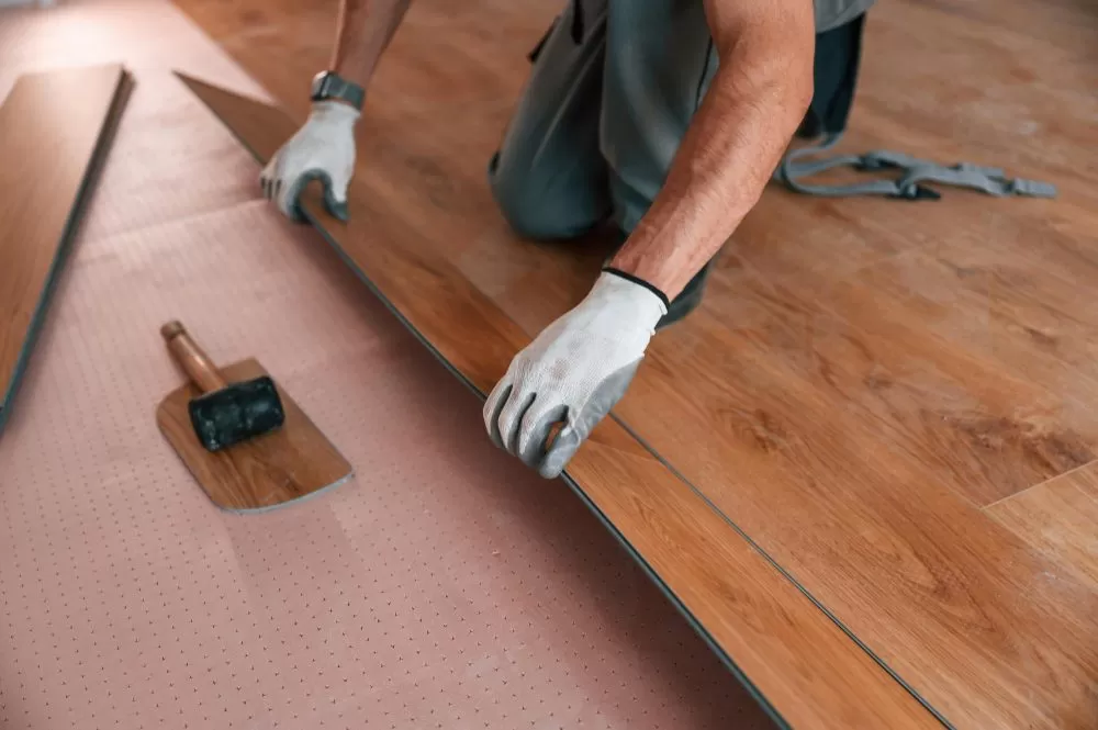 luxury-vinyl-plank-floor-installation Professional contractor installing luxury vinyl plank flooring over an underlayment during a residential flooring renovation.