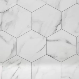 Close-up of white marble-look hexagon tile with gray veining installed in a seamless geometric pattern for a modern bathroom or kitchen.