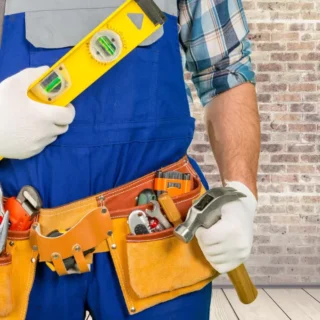 Professional handyman with tool belt holding a level and hammer for residential home repair services