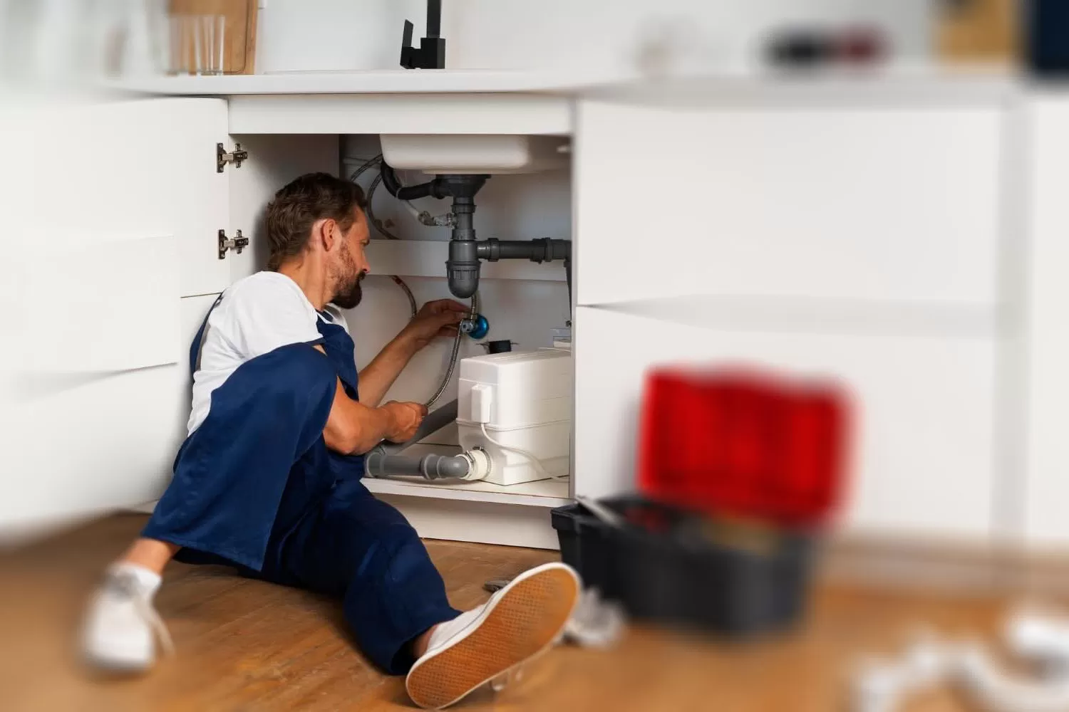 Plumber repairing plumbing beneath a kitchen sink during residential plumbing repair service