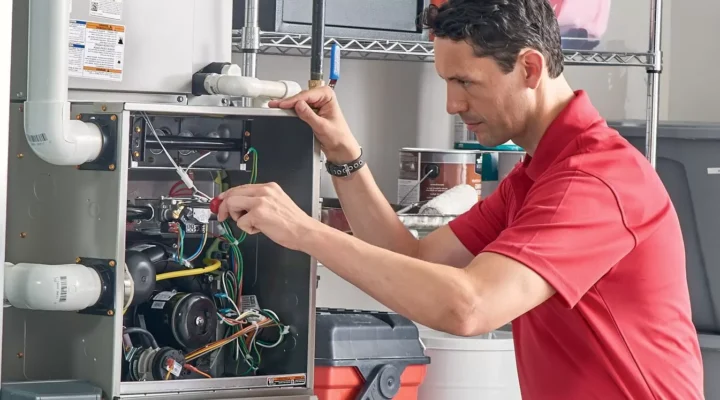 HVAC technician repairing residential furnace during professional heating system maintenance